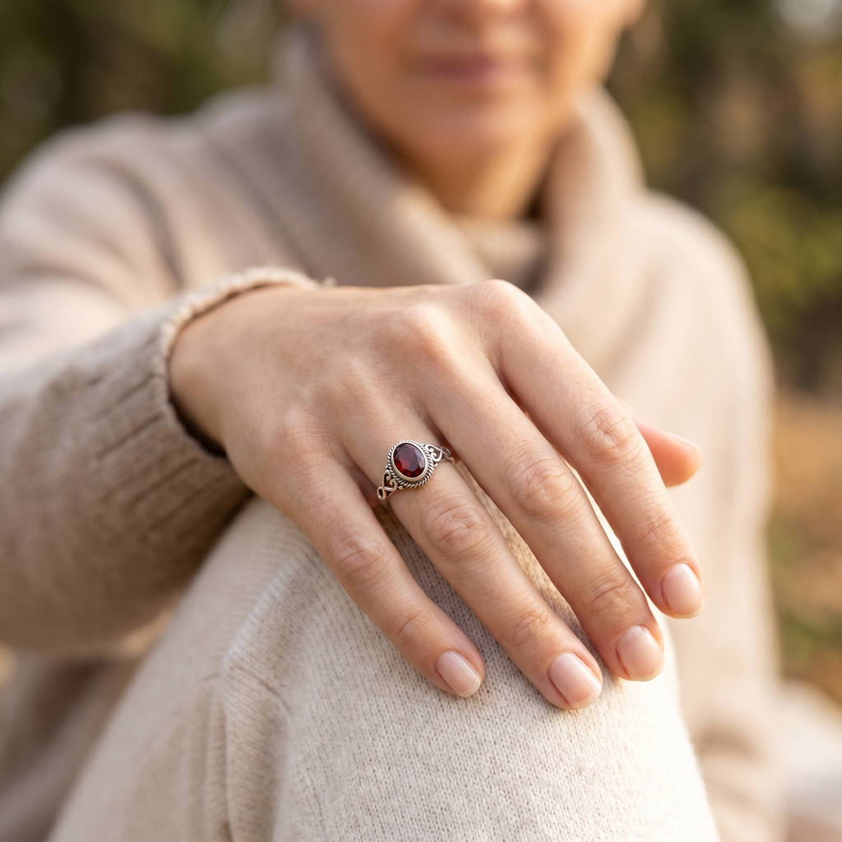 Granatring aus Silber getragen an der Hand im Freien