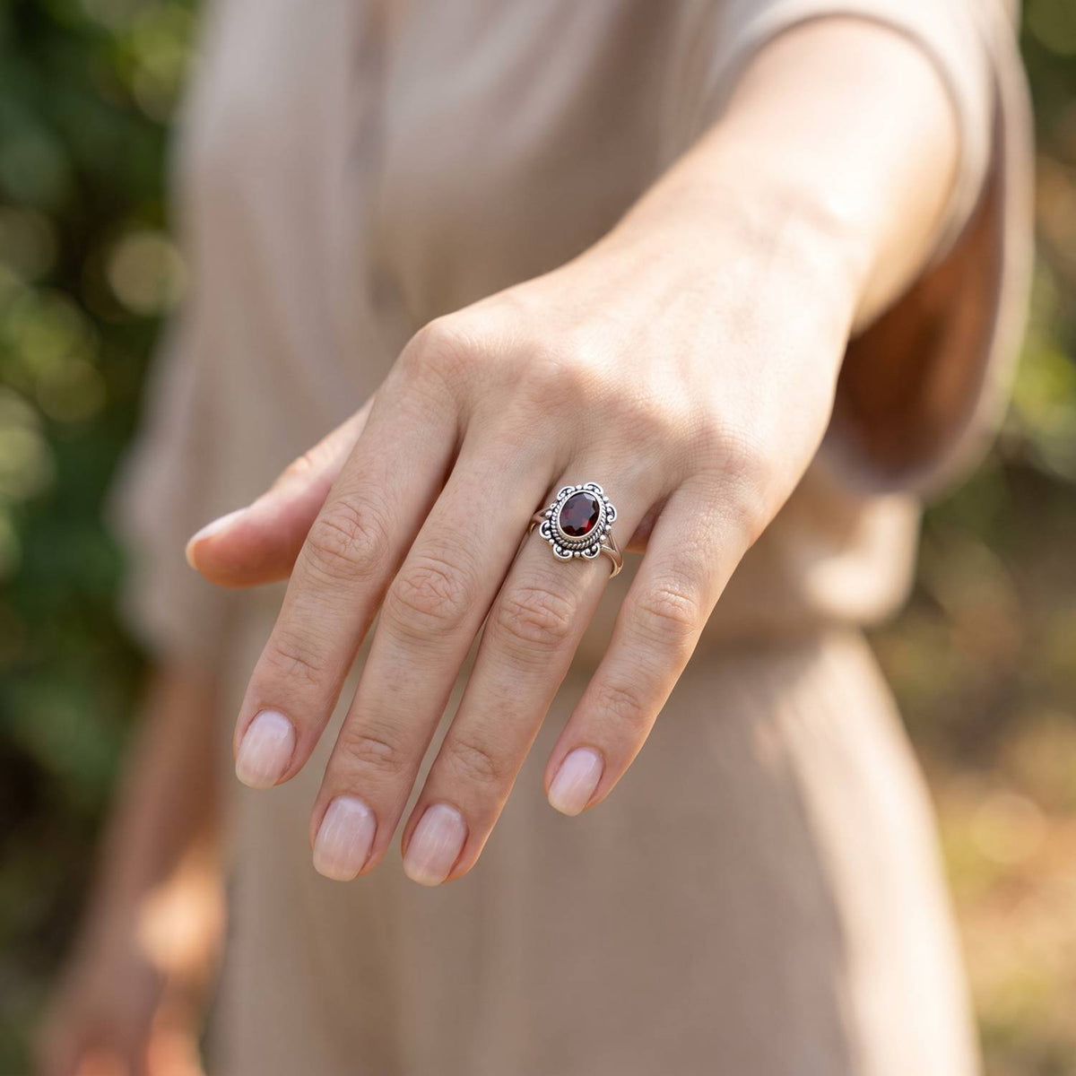 Granatring aus Silber getragen an der Hand im Freien