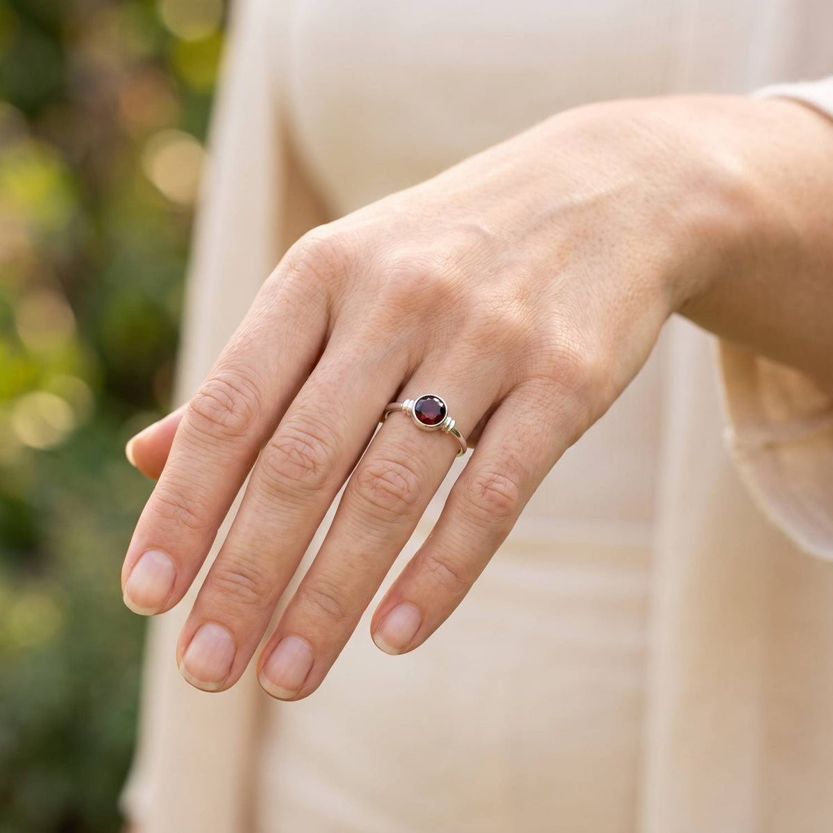 Granatring aus Silber getragen an der Hand im Freien