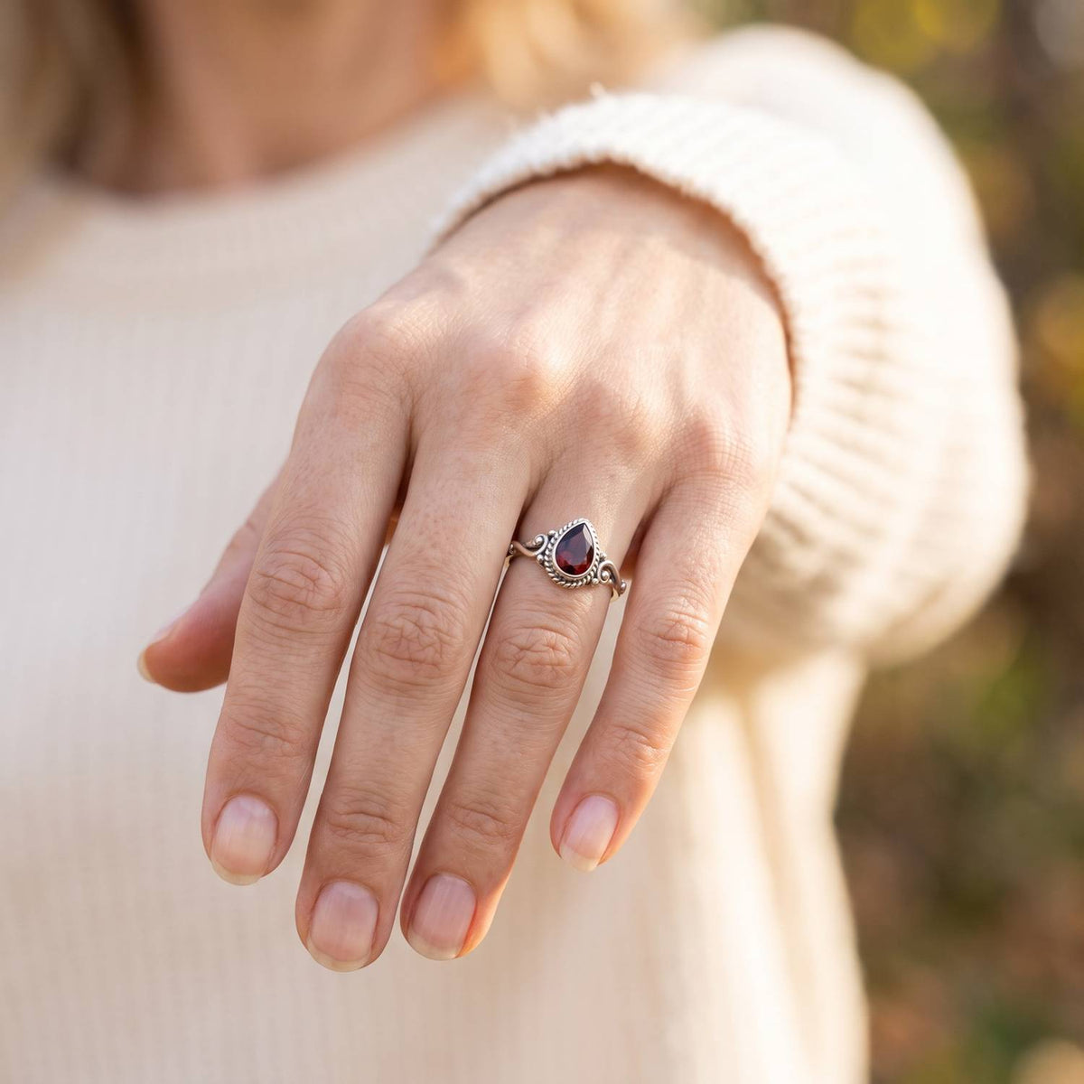 Granatring aus Silber getragen an der Hand im Freien