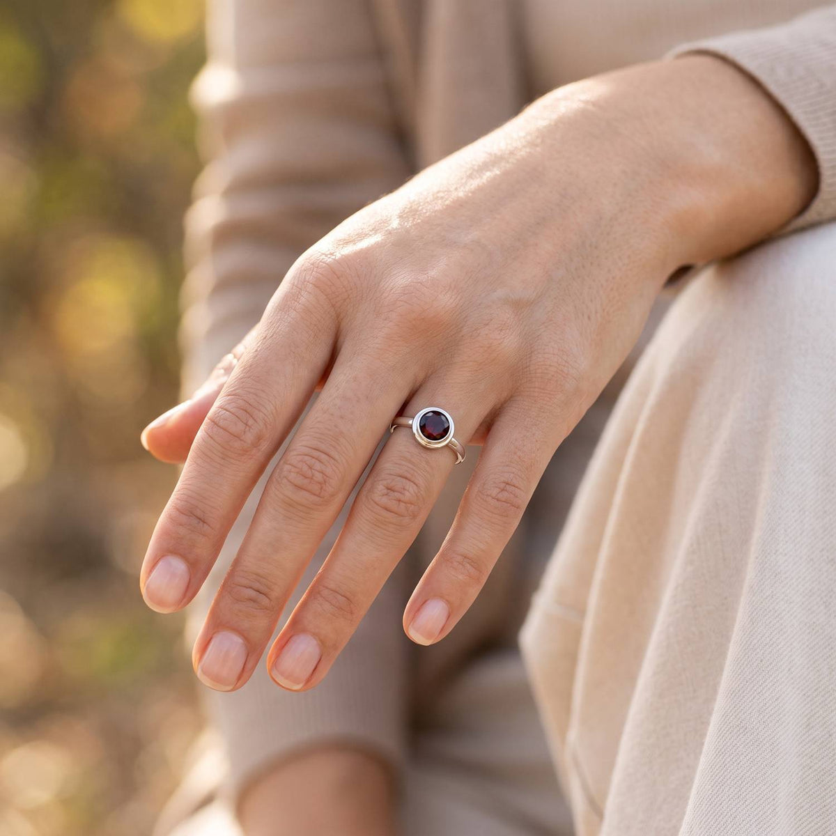Granatring aus Silber getragen an der Hand im Freien