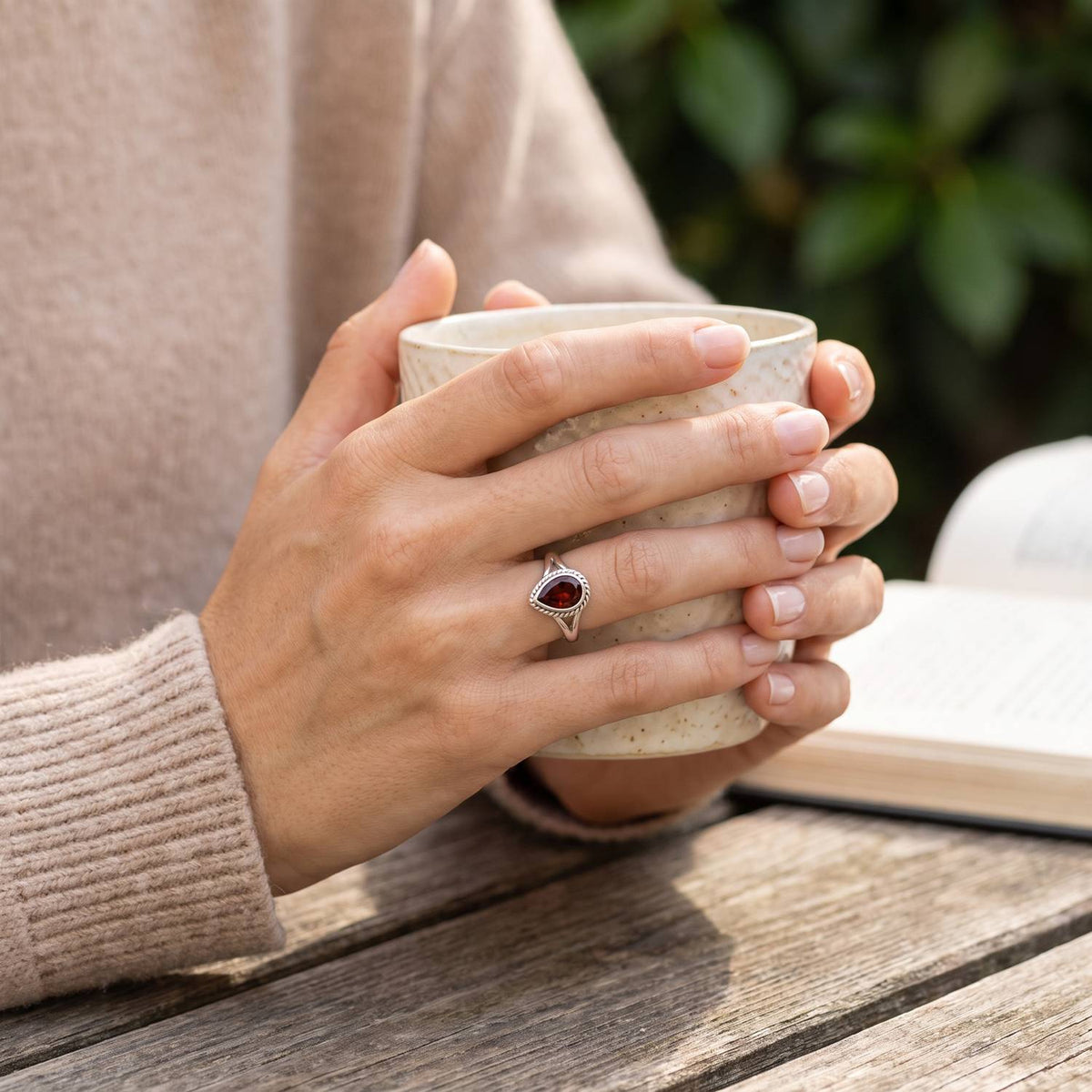 Granatring aus Silber getragen beim Lesen mit einer Tasse
