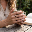 [KI] Granatring aus Silber getragen beim Lesen mit einer Tasse