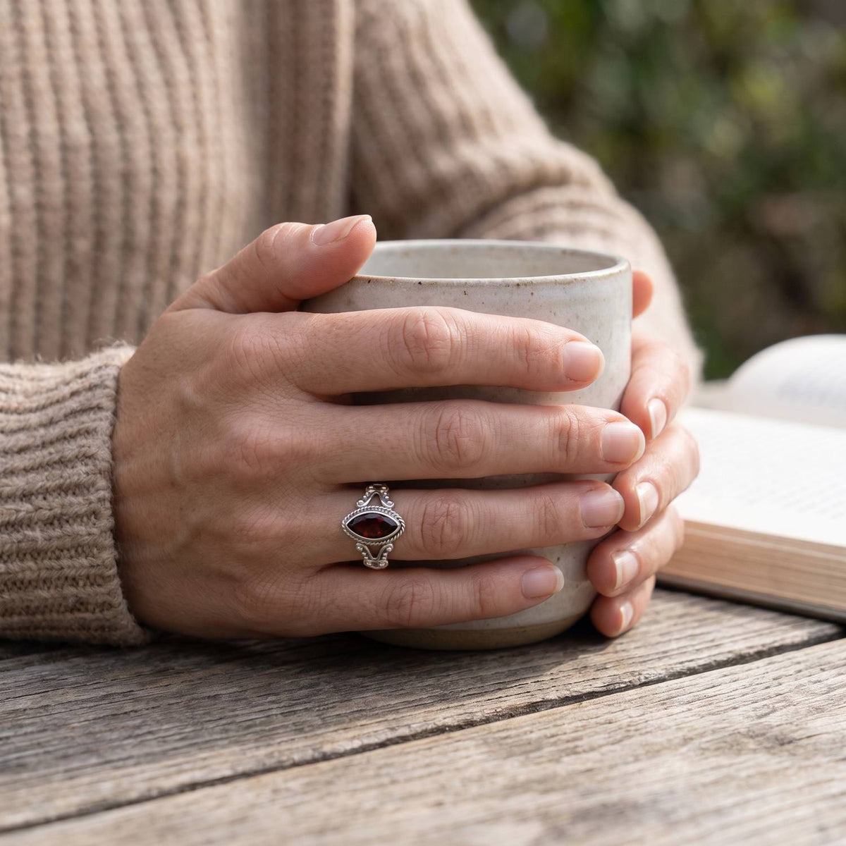 Granatring aus Silber getragen beim Lesen mit einer Tasse