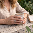 [KI] Granatring aus Silber getragen beim Lesen mit einer Tasse