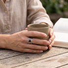 [KI] Granatring aus Silber getragen beim Lesen mit einer Tasse