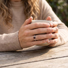 [KI] Granatring aus Silber getragen beim Lesen mit einer Tasse