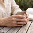 [KI] Granatring aus Silber getragen beim Lesen mit einer Tasse