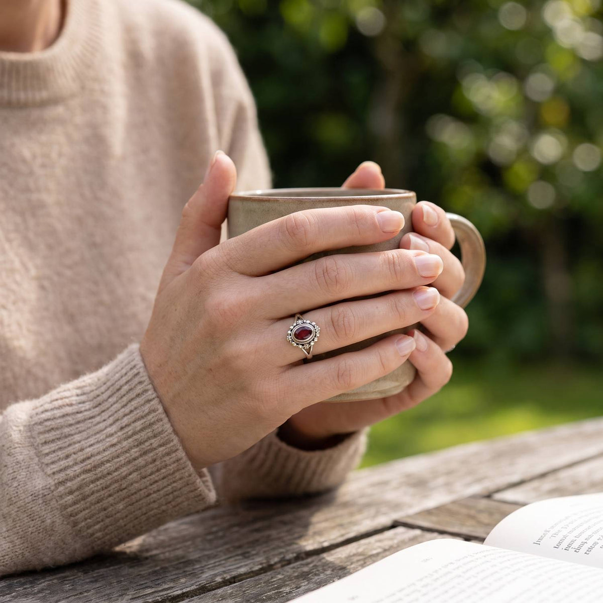 Granatring aus Silber getragen beim Lesen mit einer Tasse