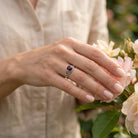 [KI] Silberring mit Granat an der Hand zwischen Blumen
