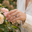 [KI] Silberring mit Granat an der Hand zwischen Blumen