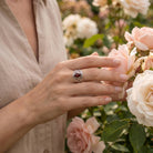 [KI] Silberring mit Granat an der Hand zwischen Blumen
