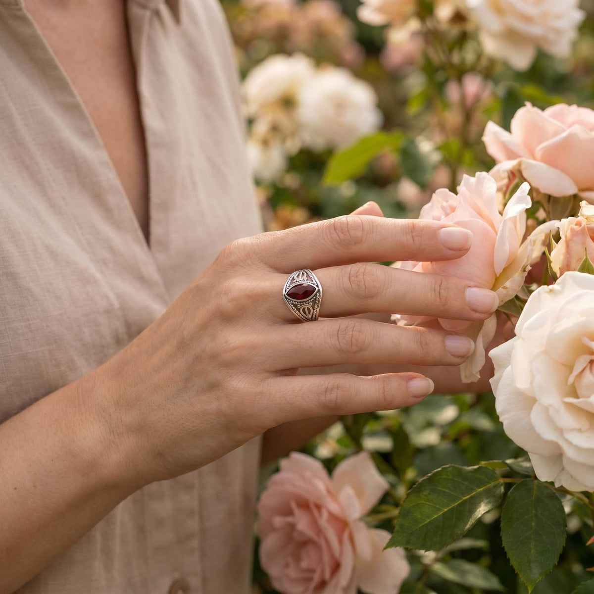 Silberring mit Granat an der Hand zwischen Blumen