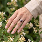 [KI] Silberring mit Granat an der Hand zwischen Blumen