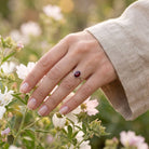 [KI] Silberring mit Granat an der Hand zwischen Blumen