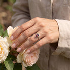 [KI] Silberring mit Granat an der Hand zwischen Blumen