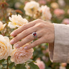 [KI] Silberring mit Granat an der Hand zwischen Blumen