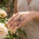 [KI] Silberring mit Granat an der Hand zwischen Blumen
