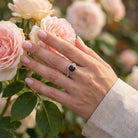 [KI] Silberring mit Granat an der Hand zwischen Blumen