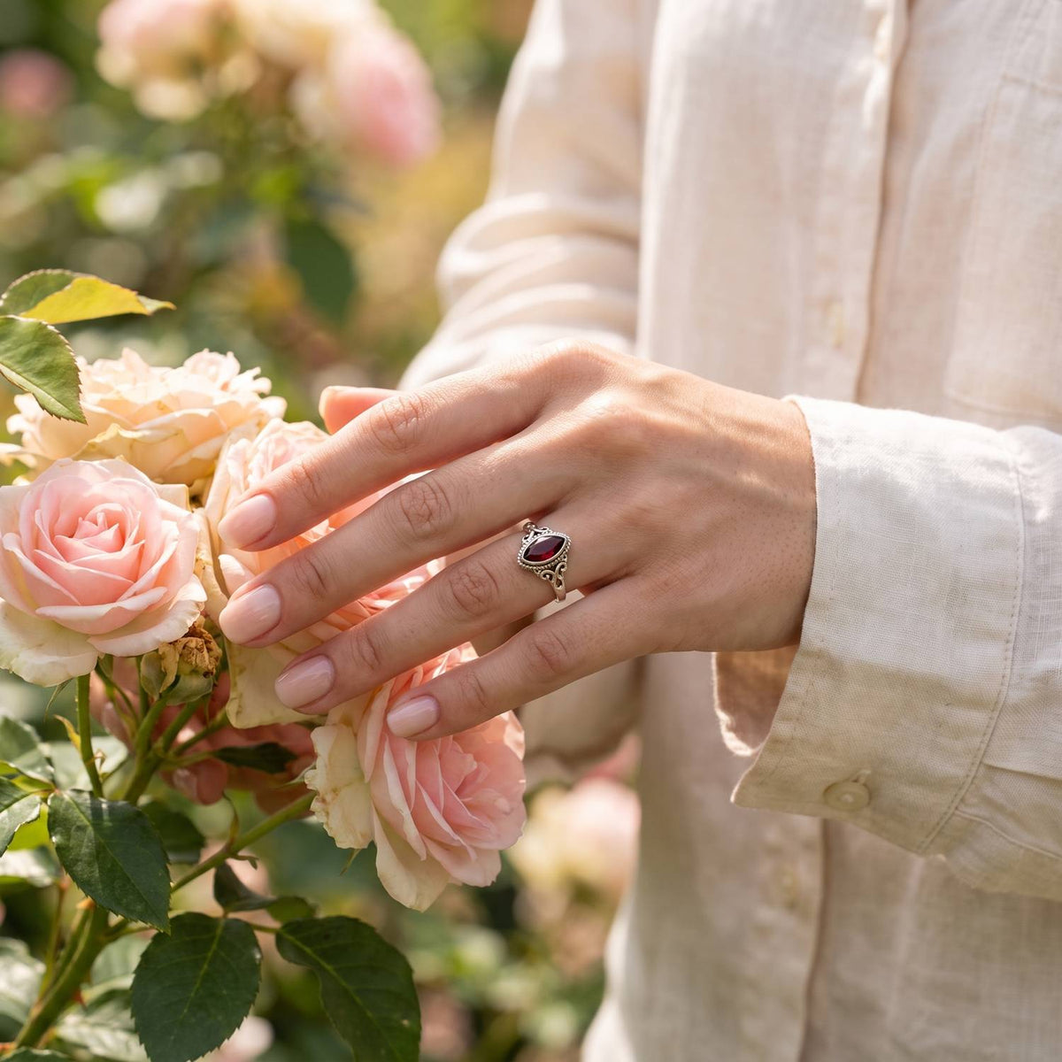 Silberring mit Granat an der Hand zwischen Blumen