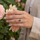 [KI] Silberring mit Granat an der Hand zwischen Blumen