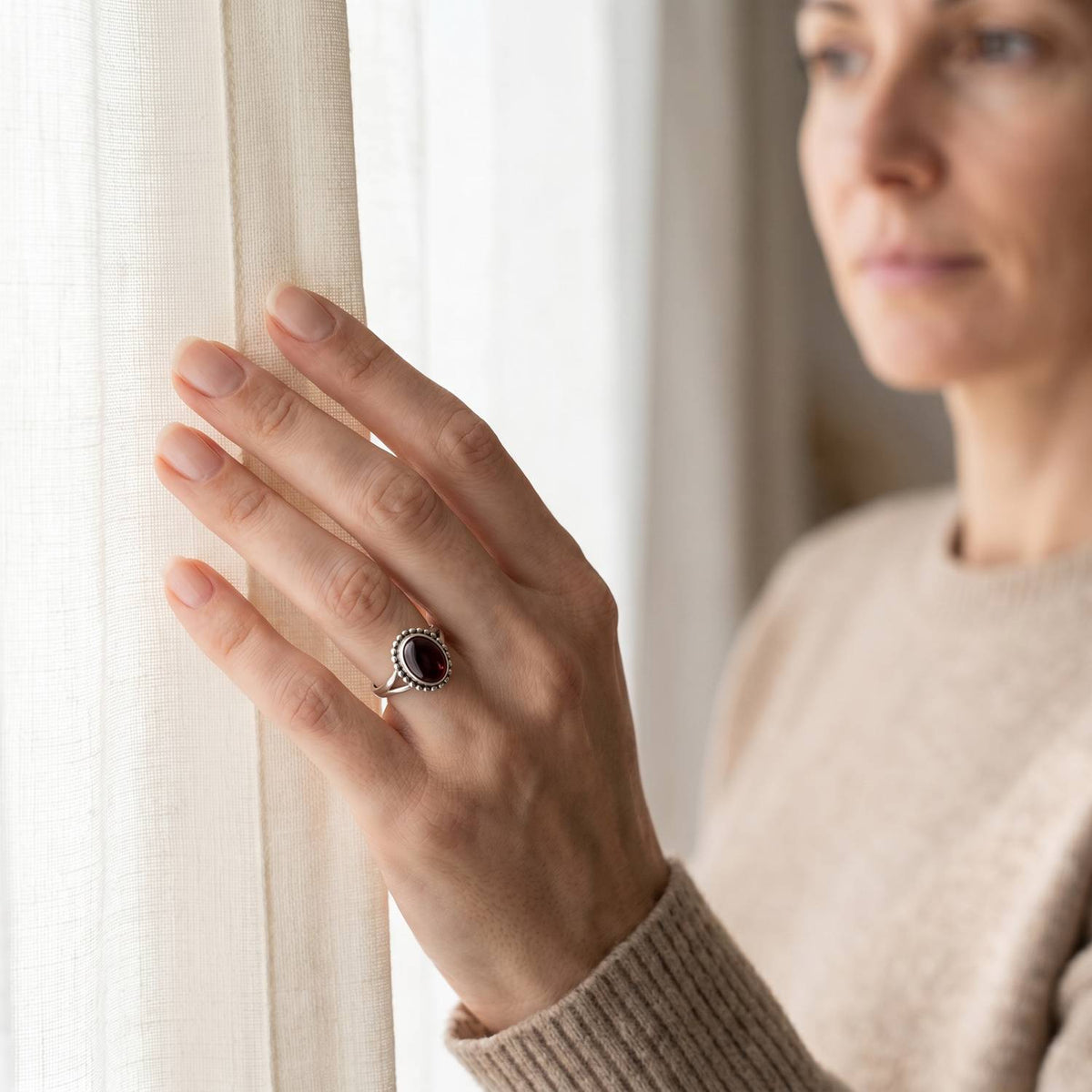 Frau trägt einen Granatring aus Silber am Fenster