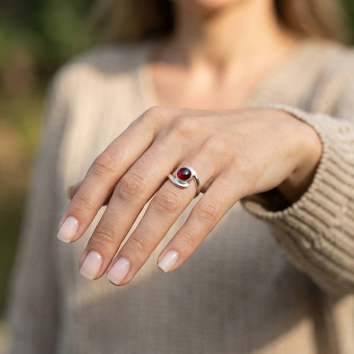 Granatring aus Silber getragen an der Hand im Freien