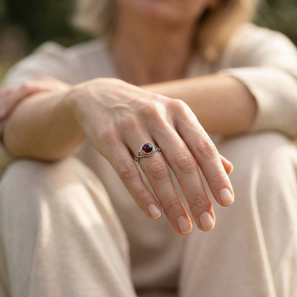 Granatring aus Silber getragen an der Hand im Freien
