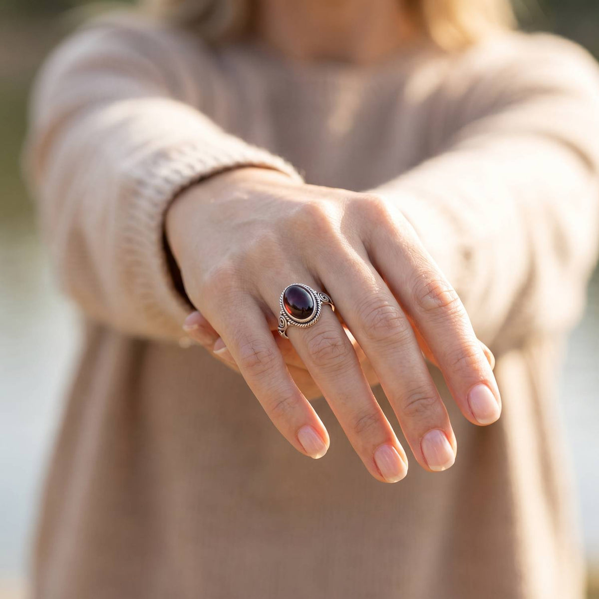 Granatring aus Silber getragen an der Hand im Freien