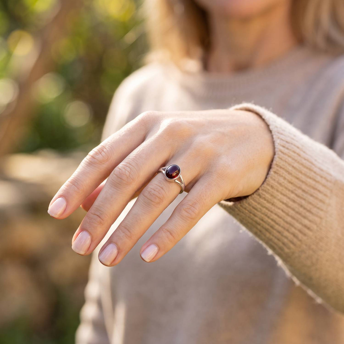 Granatring aus Silber getragen an der Hand im Freien