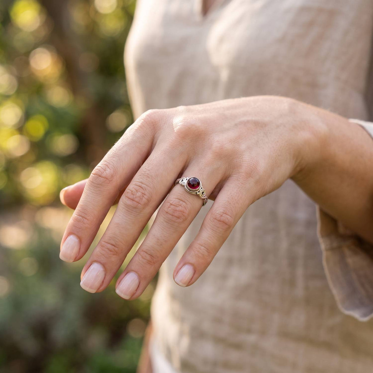 Granatring aus Silber getragen an der Hand im Freien