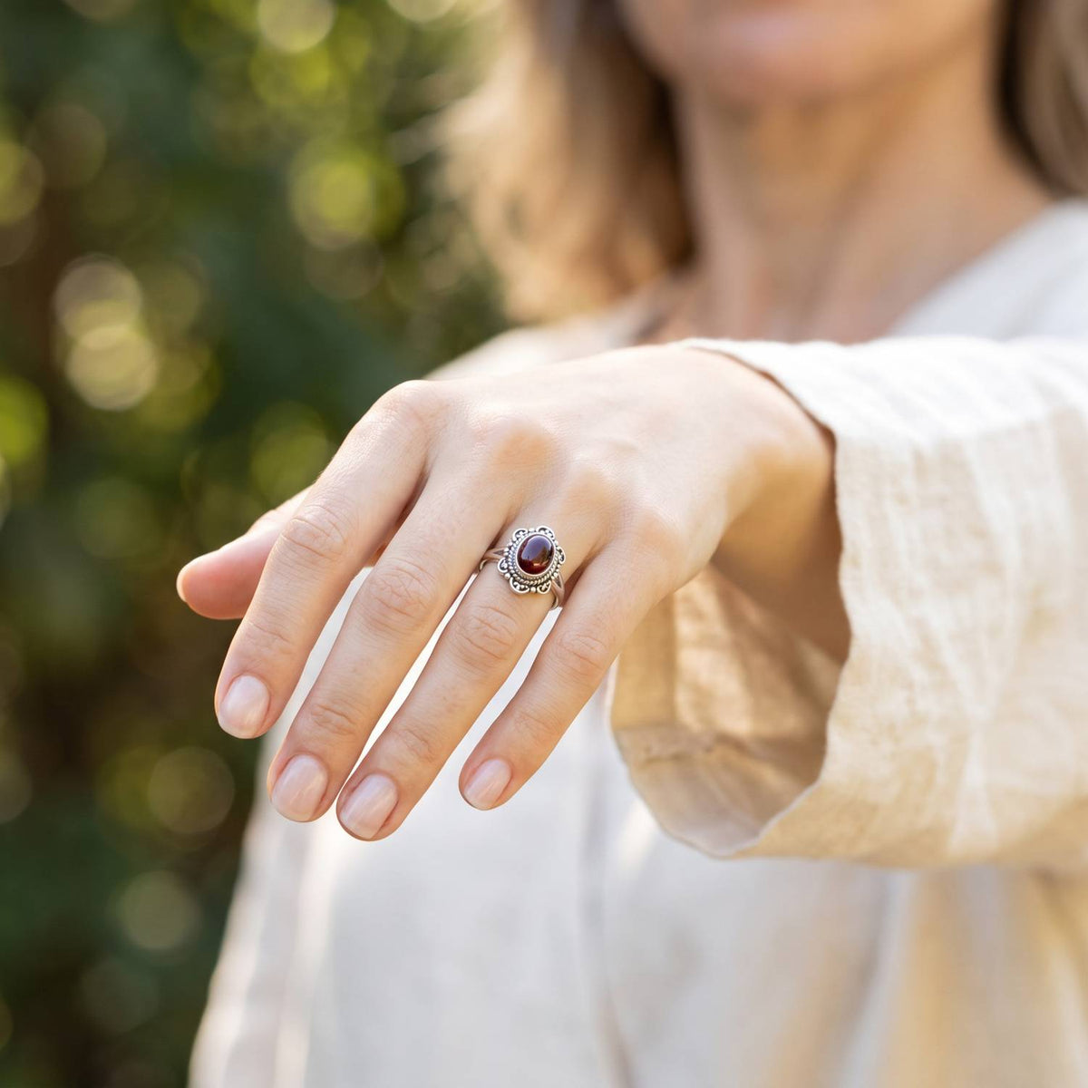 Granatring aus Silber getragen an der Hand im Freien