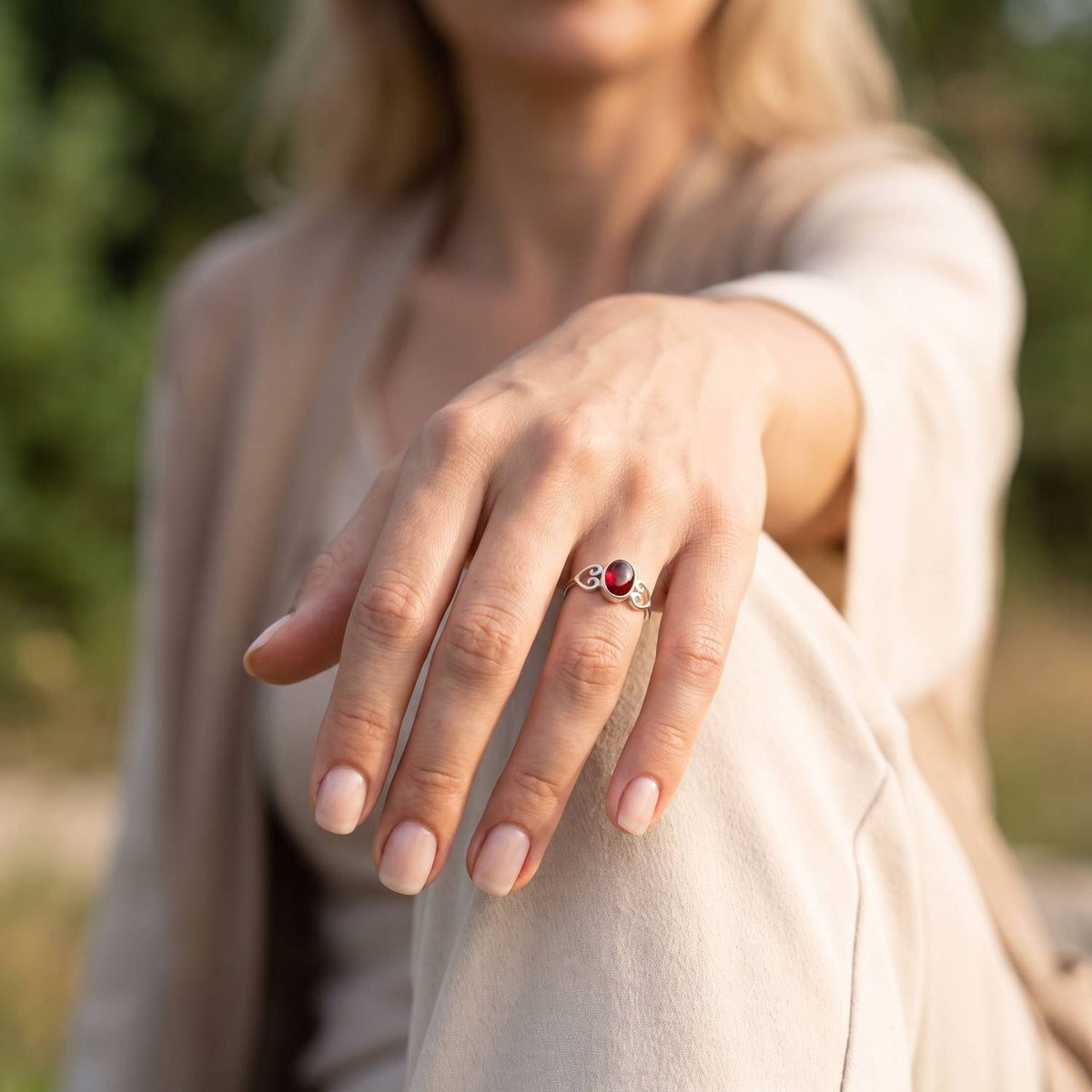 Granatring aus Silber getragen an der Hand im Freien