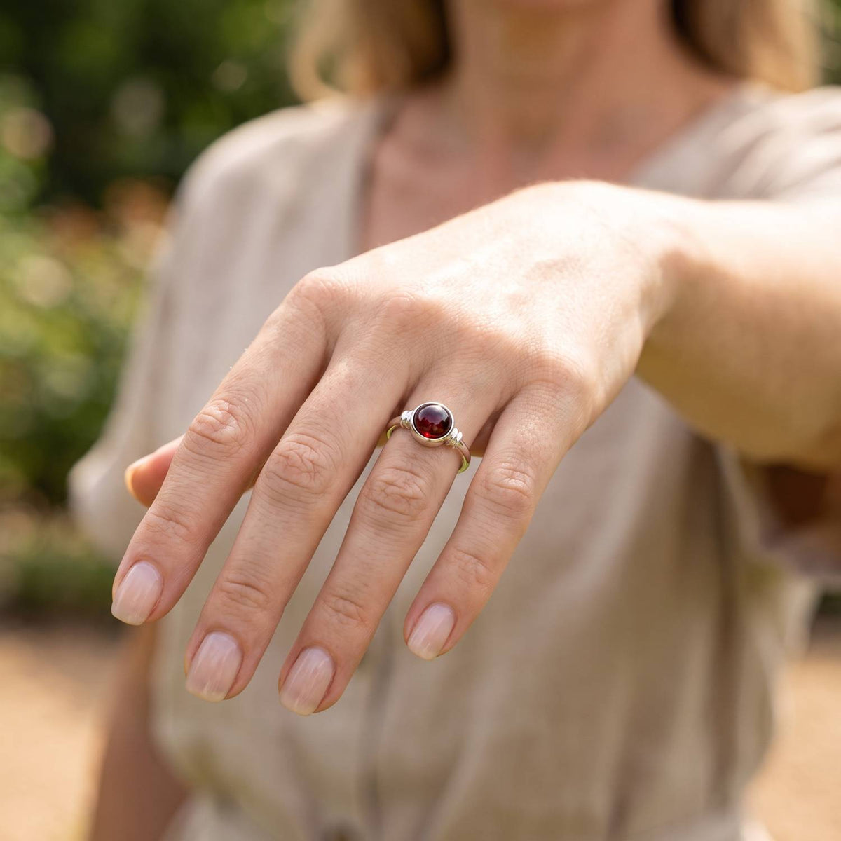 Granatring aus Silber getragen an der Hand im Freien