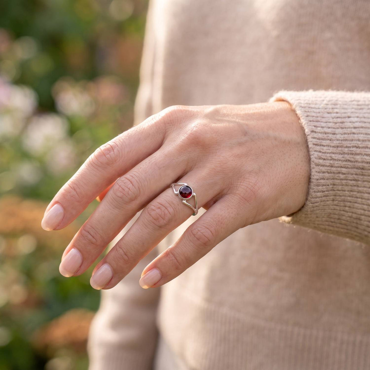 Granatring aus Silber getragen an der Hand im Freien