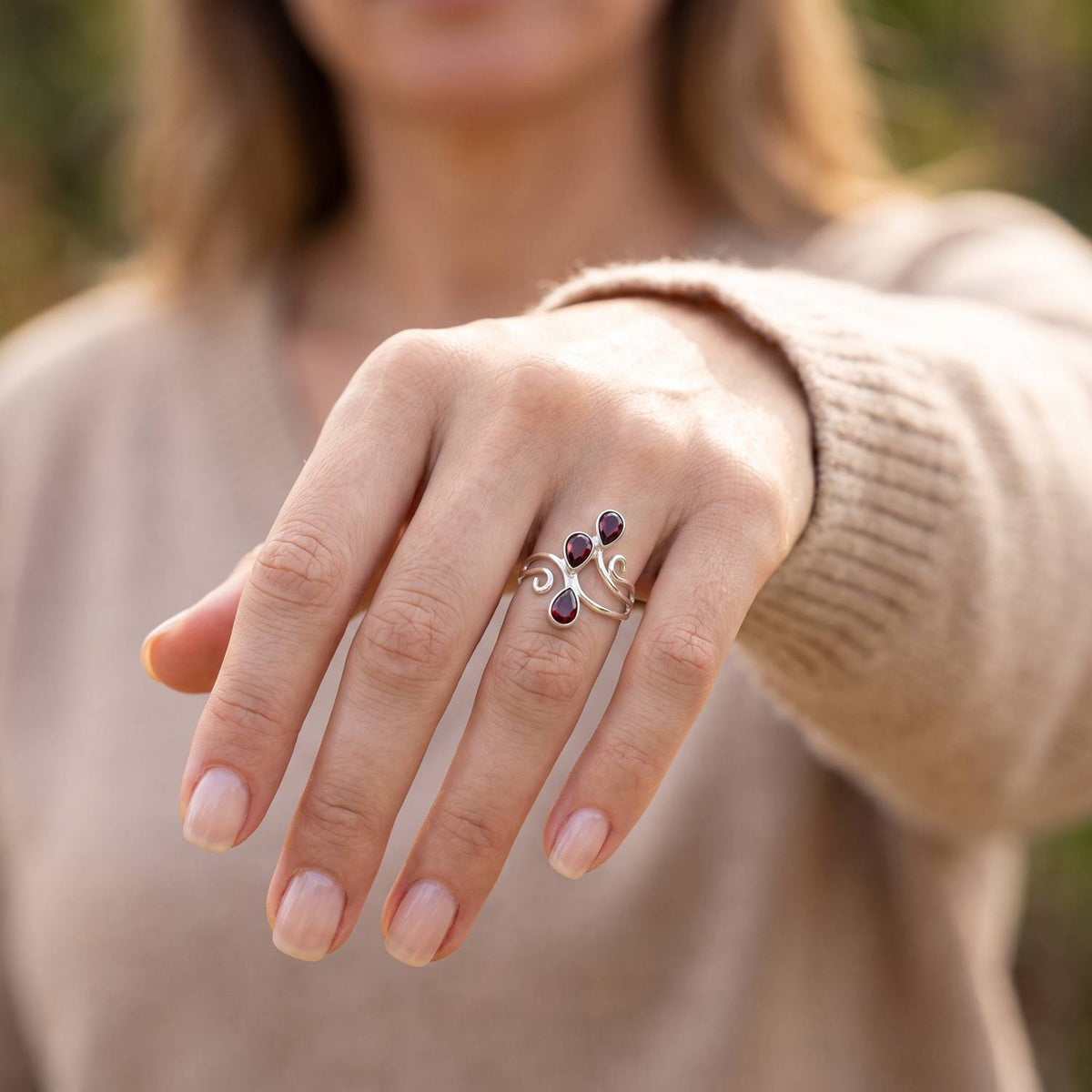 Granatring aus Silber getragen an der Hand im Freien
