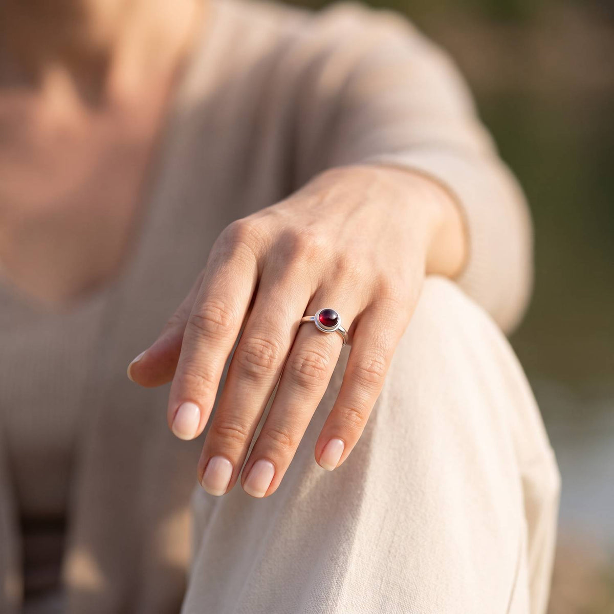 Granatring aus Silber getragen an der Hand im Freien