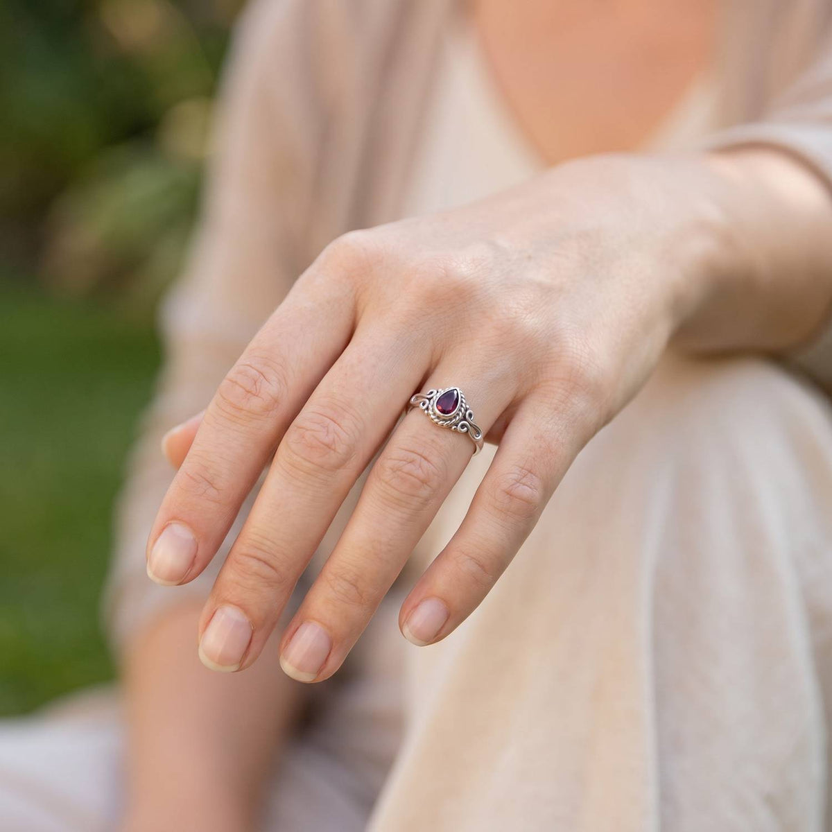 Granatring aus Silber getragen an der Hand im Freien