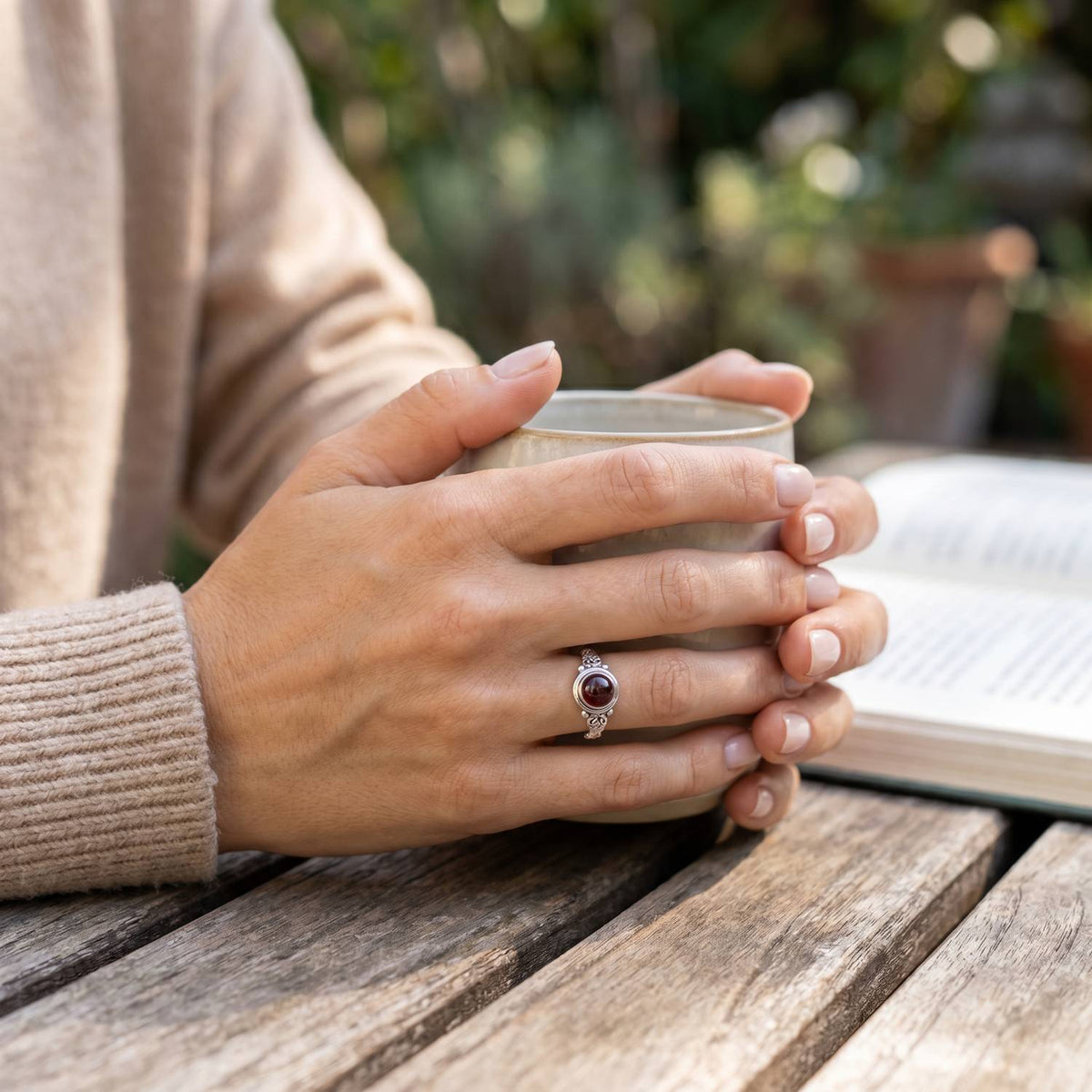 Granatring aus Silber getragen beim Lesen mit einer Tasse