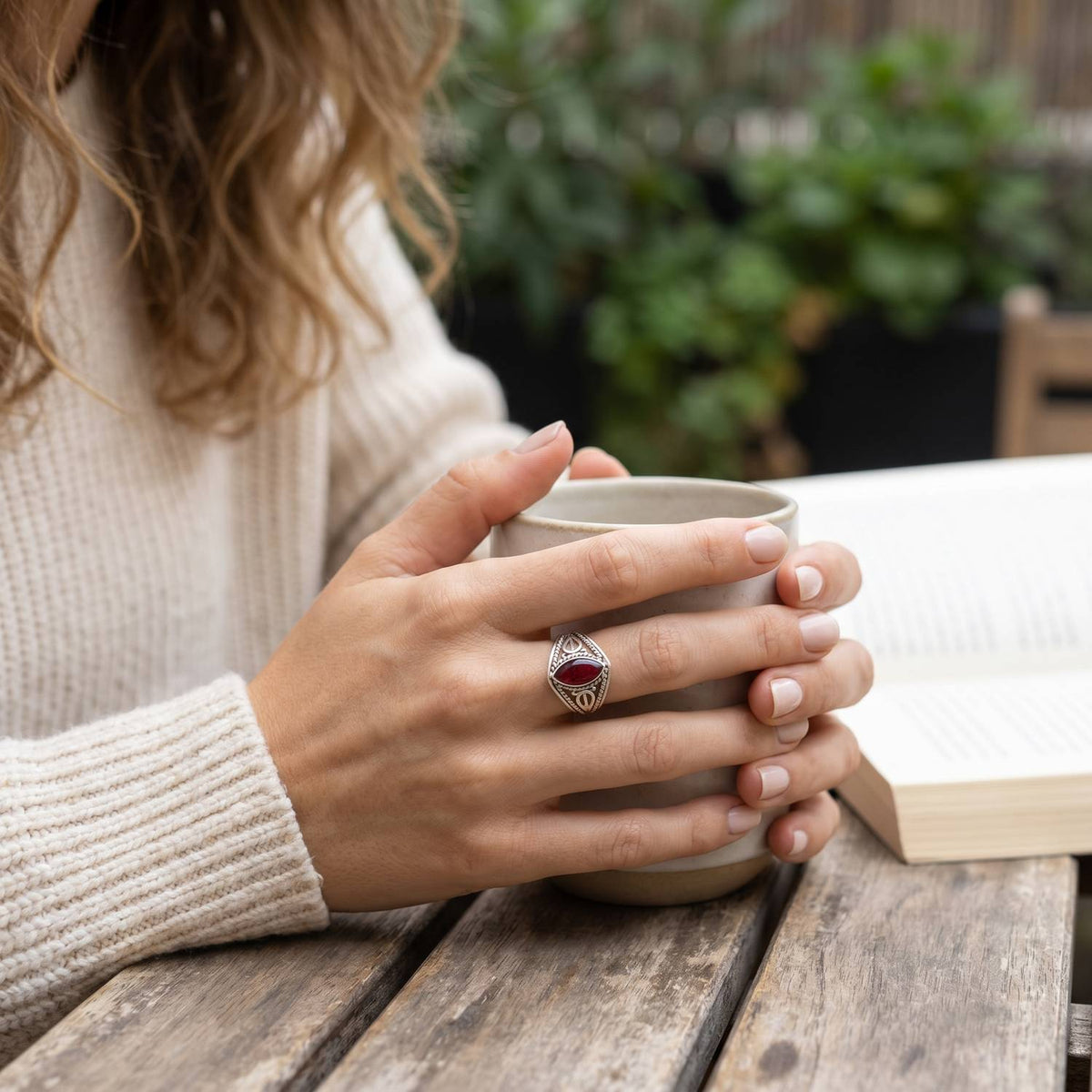 Granatring aus Silber getragen beim Lesen mit einer Tasse