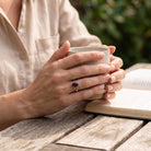 [KI] Granatring aus Silber getragen beim Lesen mit einer Tasse