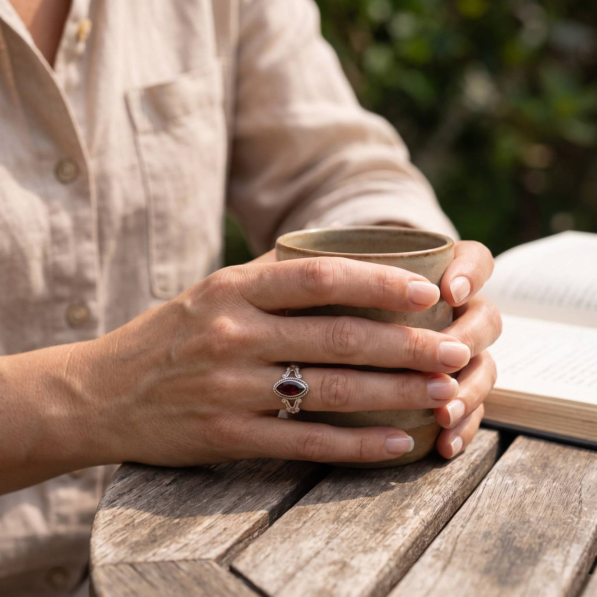 Granatring aus Silber getragen beim Lesen mit einer Tasse