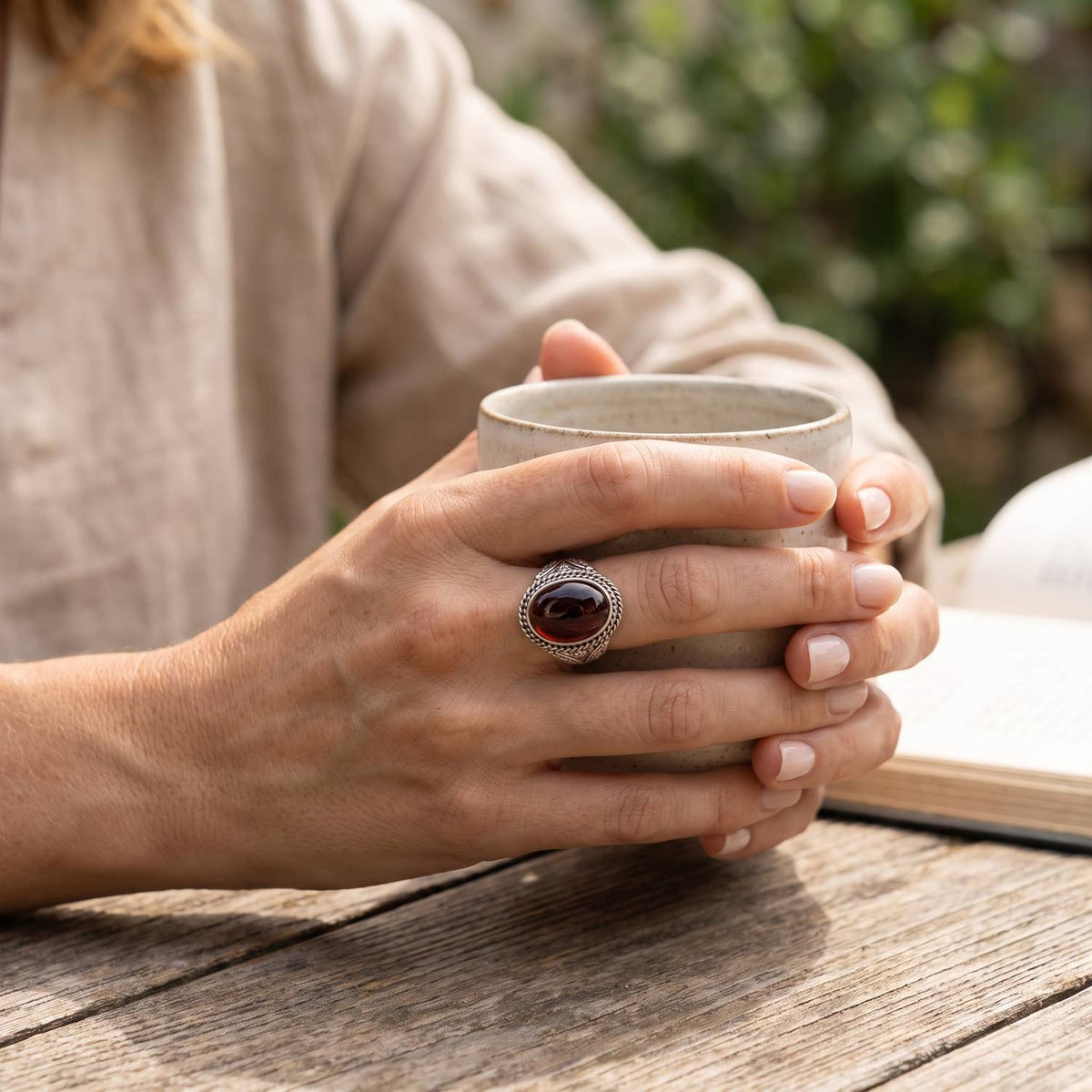 Granatring aus Silber getragen beim Lesen mit einer Tasse