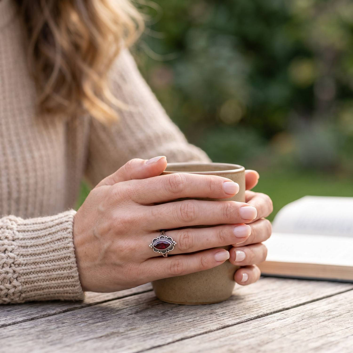 Granatring aus Silber getragen beim Lesen mit einer Tasse
