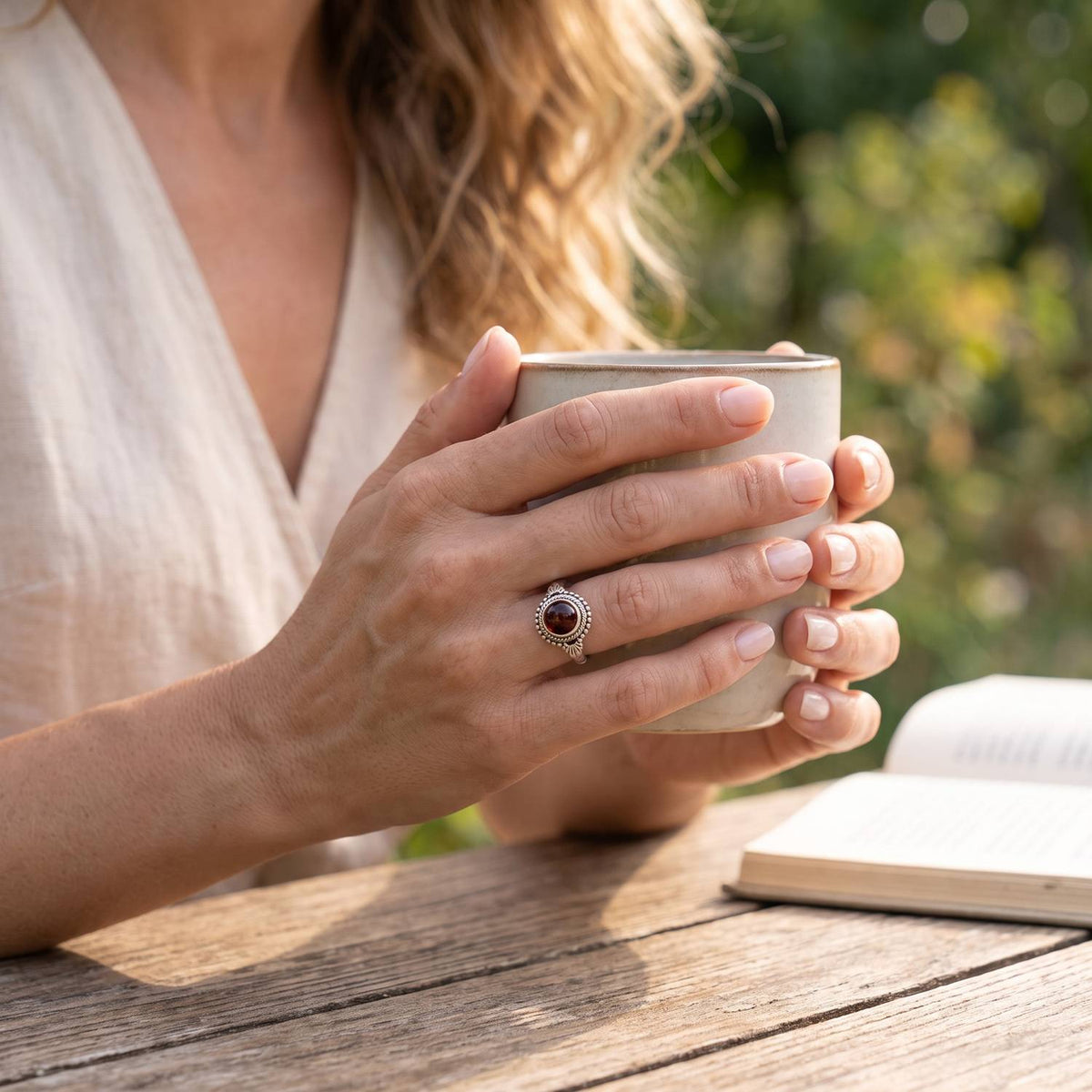 Granatring aus Silber getragen beim Lesen mit einer Tasse