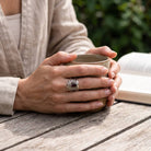 [KI] Granatring aus Silber getragen beim Lesen mit einer Tasse