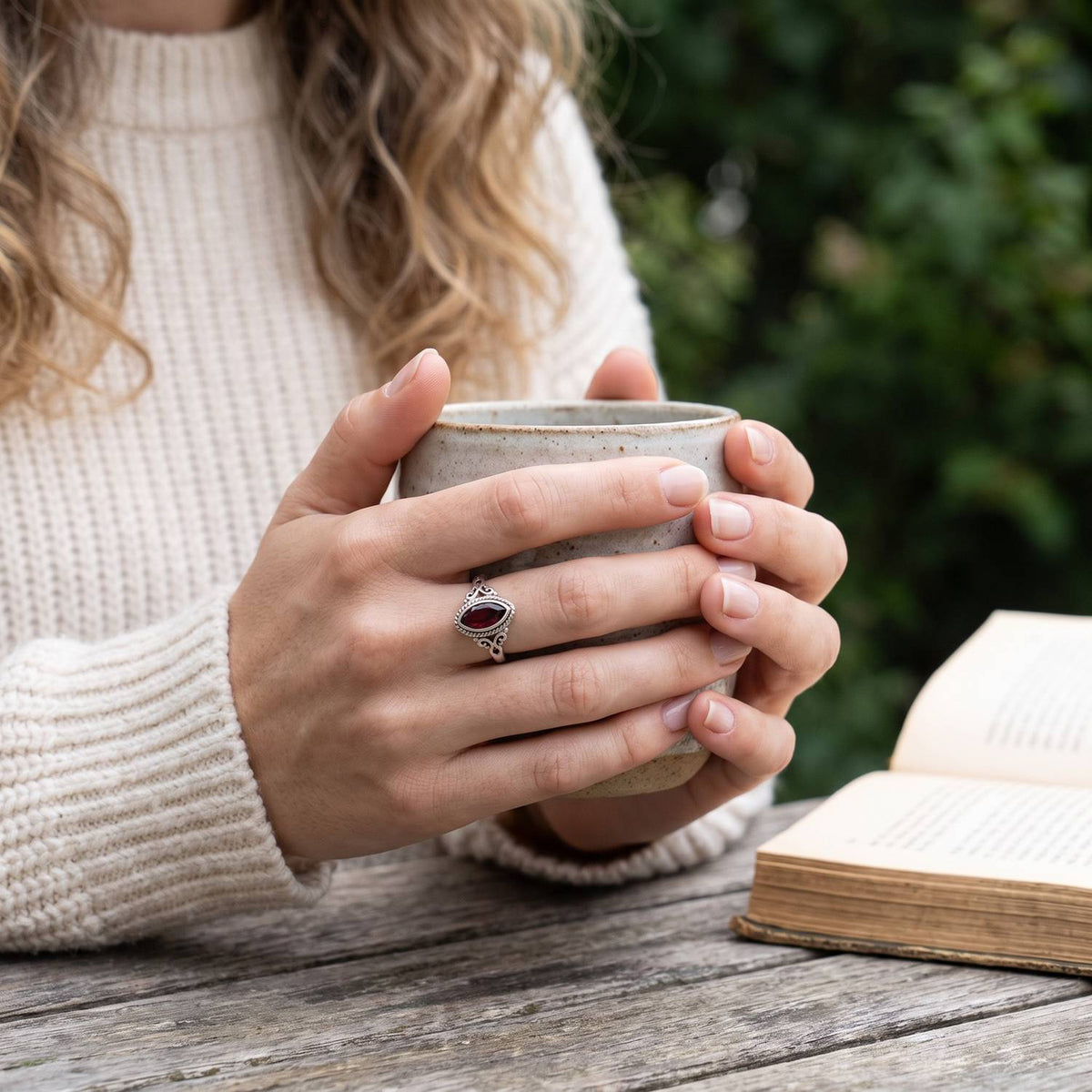 Granatring aus Silber getragen beim Lesen mit einer Tasse