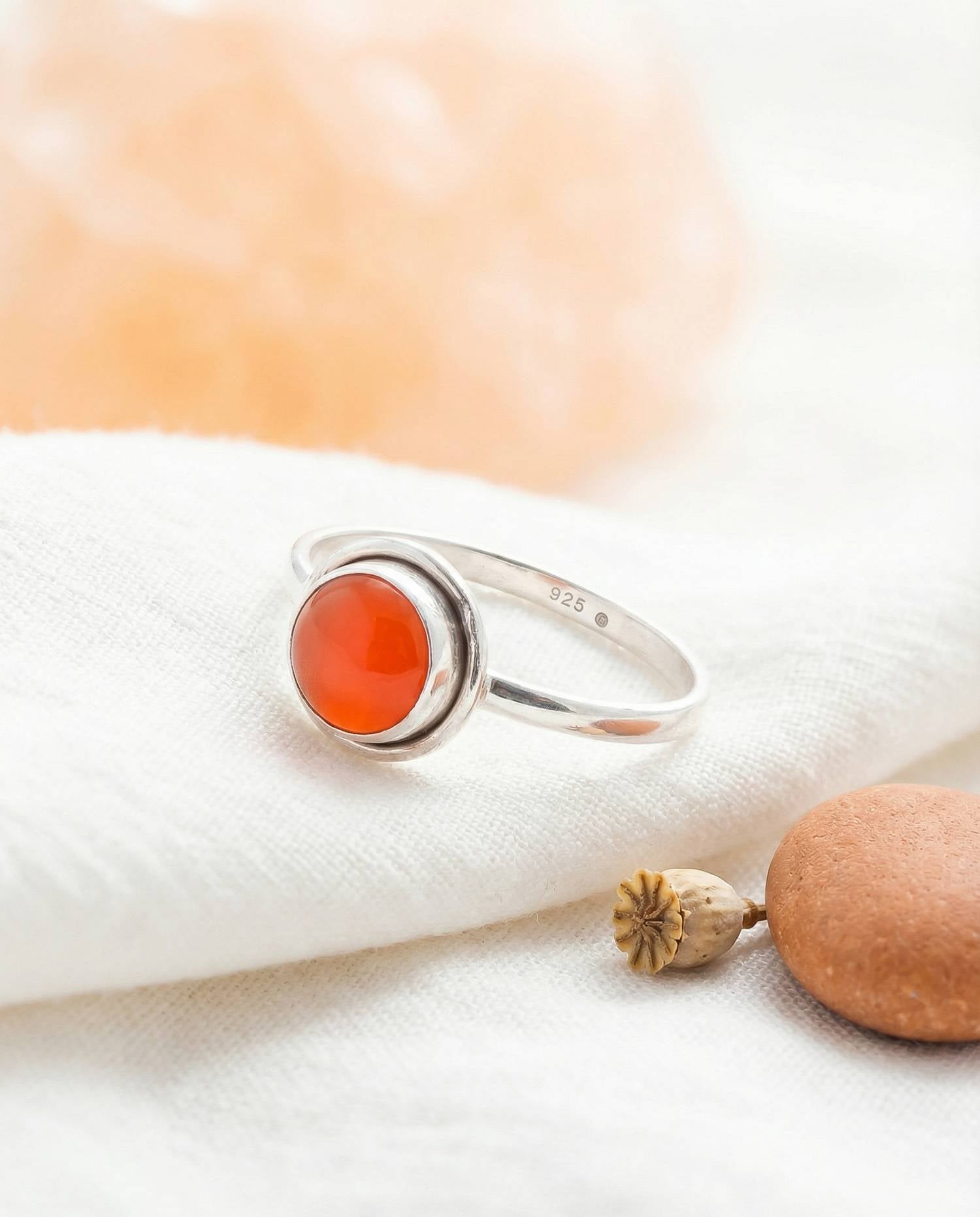 Silberring mit Karneol auf hellem Stoff