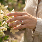 [KI] Silberring mit Karneol an der Hand zwischen Blumen