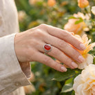 [KI] Silberring mit Karneol an der Hand zwischen Blumen